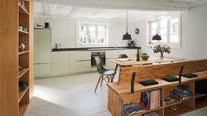 Una cucina moderna con zona pranzo, arredi in legno e una libreria.