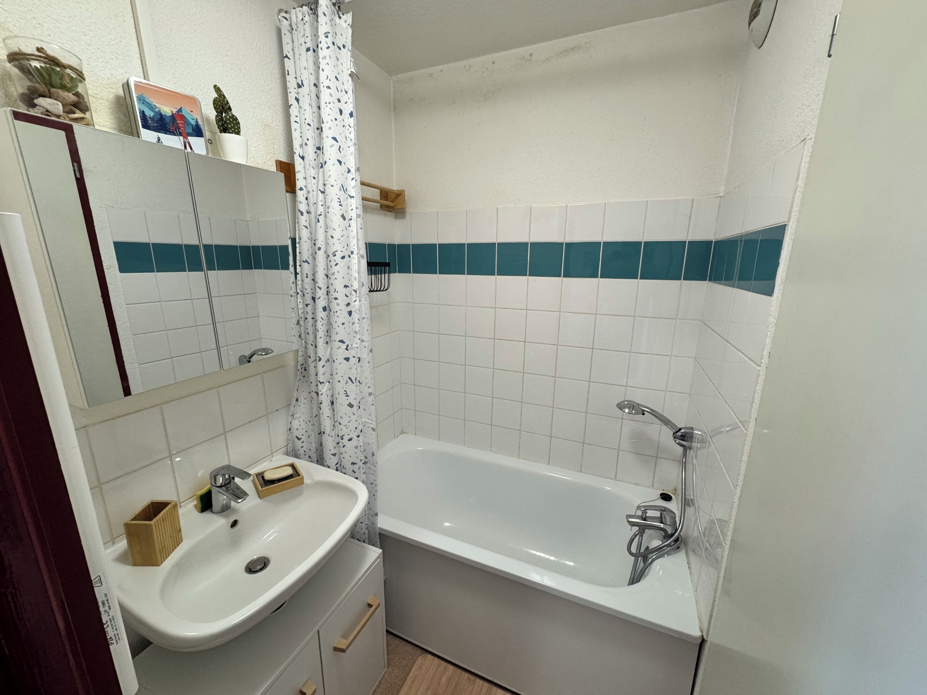 A bathroom with a white sink, a bathtub, and a shower curtain.