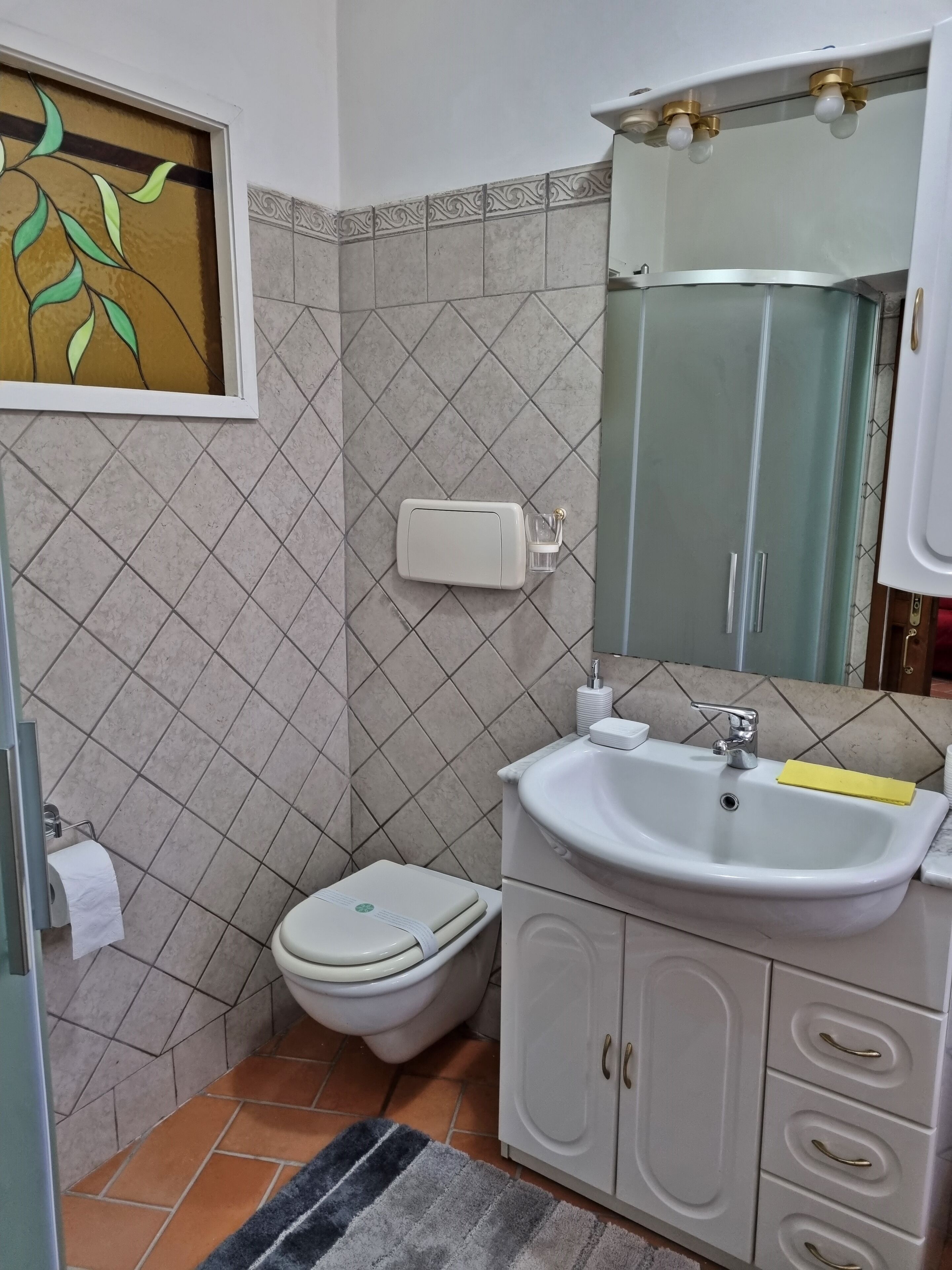 Un baño con inodoro, lavamanos y mueble de almacenamiento.