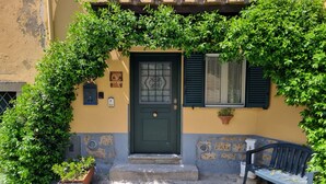 A building with a green door, a mailbox, and a bench outside. - Nives Holiday House, home in the ancient castle walls in the historic center. (Tuscania)