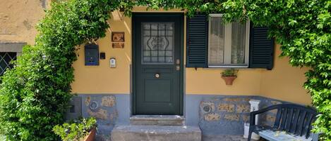 A building with a green door, a mailbox, and a bench outside.