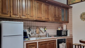 A kitchen with wooden cabinets, a refrigerator, a microwave, a stove, and a sink. - Nives Holiday House, home in the ancient castle walls in the historic center. (Tuscania)