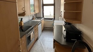 Eine kleine Küche mit Holdekor, einer schwarzen Arbeitsplatte und einem Fenster, das natürliches Licht hereinlässt.