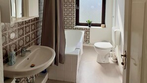 Ein Badezimmer mit Waschbecken, Spiegel, Dusche und Toilette.