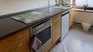 Eine Küche mit Holzschränken, einem Herd und einem Fenster.
