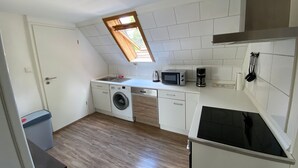 Cocina compacta con lavadora, microondas y cafetera.