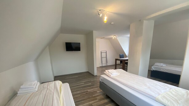 Una habitación de hotel moderna con dos camas, un televisor de pantalla plana y un escritorio con una silla.