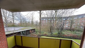 Ein Eckzimmer mit Fliesenboden, einer grünen Wand und Blick auf einen Garten und Gebäude.
