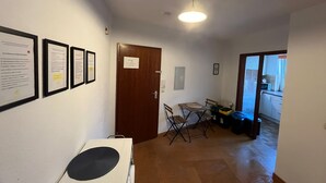 Ein Flur mit gerahmten Dokumenten an der Wand, einer Tür, einem Tisch mit Stühlen und einer kleinen Küchenzeile im Hintergrund.