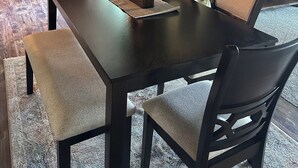 A dining area with a dark wooden table, cushioned chairs, and a vase with dried flowers. There is a kitchen in the background with wooden cabinets and a microwave. - Lake cabin 2-bedroom sleeps 6.  1/2 mile from trails.  Backus with private dock. (Backus)