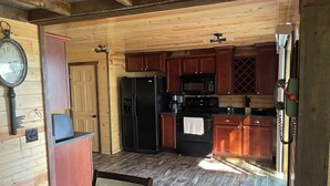A compact kitchen with wooden cabinets, a refrigerator, a microwave, and a coffee maker. - Lake cabin 2-bedroom sleeps 6.  1/2 mile from trails.  Backus with private dock. (Backus)