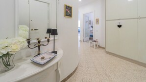 Une salle de bain avec un meuble-lavabo blanc, un miroir, un vase avec des fleurs blanches, une lampe noire et un plateau bleu et blanc.