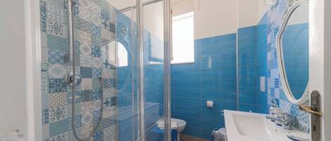 Un baño con ducha, inodoro, lavabo y espejo.