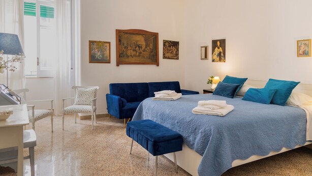 Une chambre à coucher avec un lit, un bureau, une chaise et des œuvres d’art accrochées au mur.