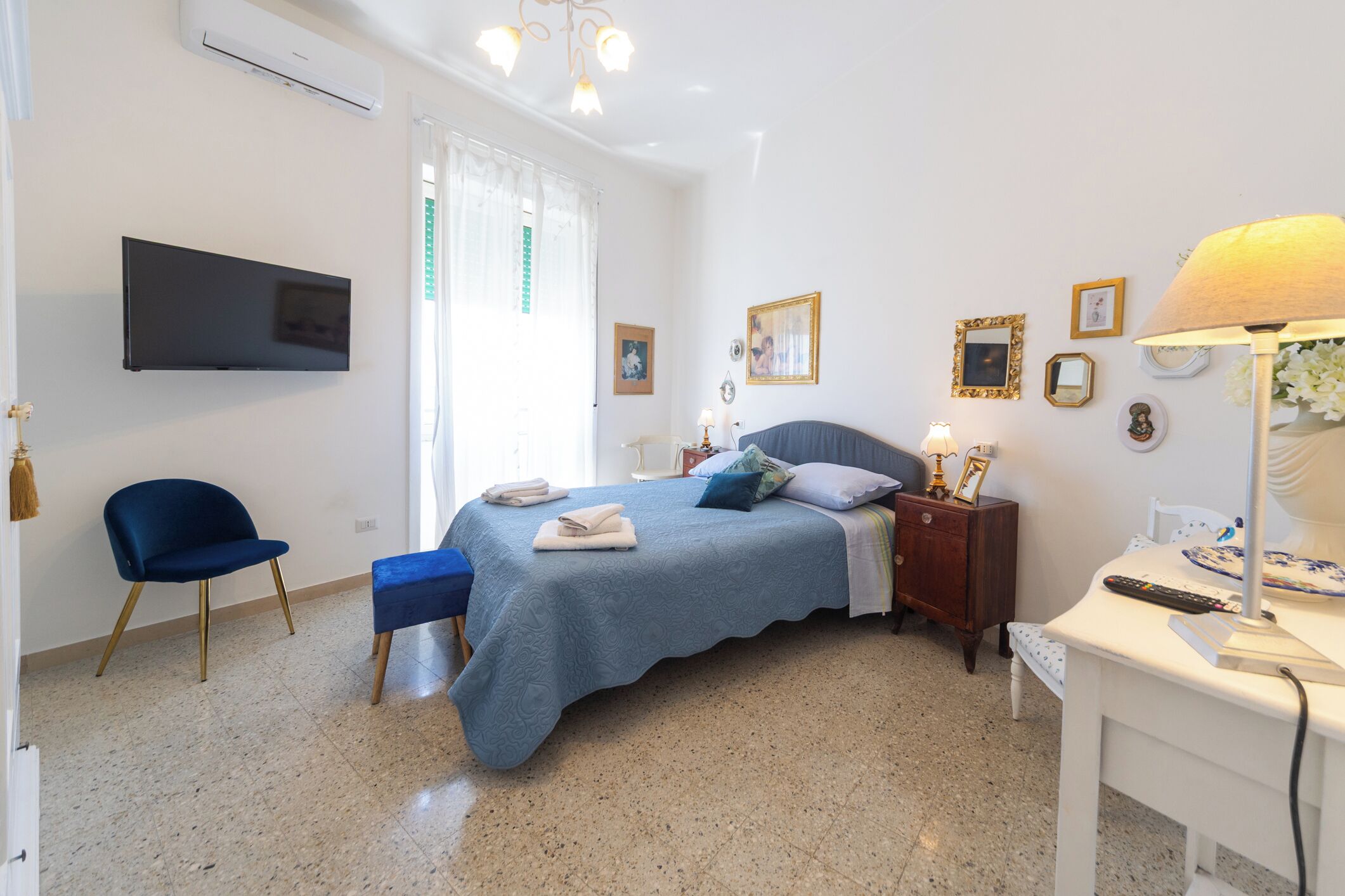Ein Schlafzimmer mit Bett, Schreibtisch, Sessel, Fernseher und Lampe.