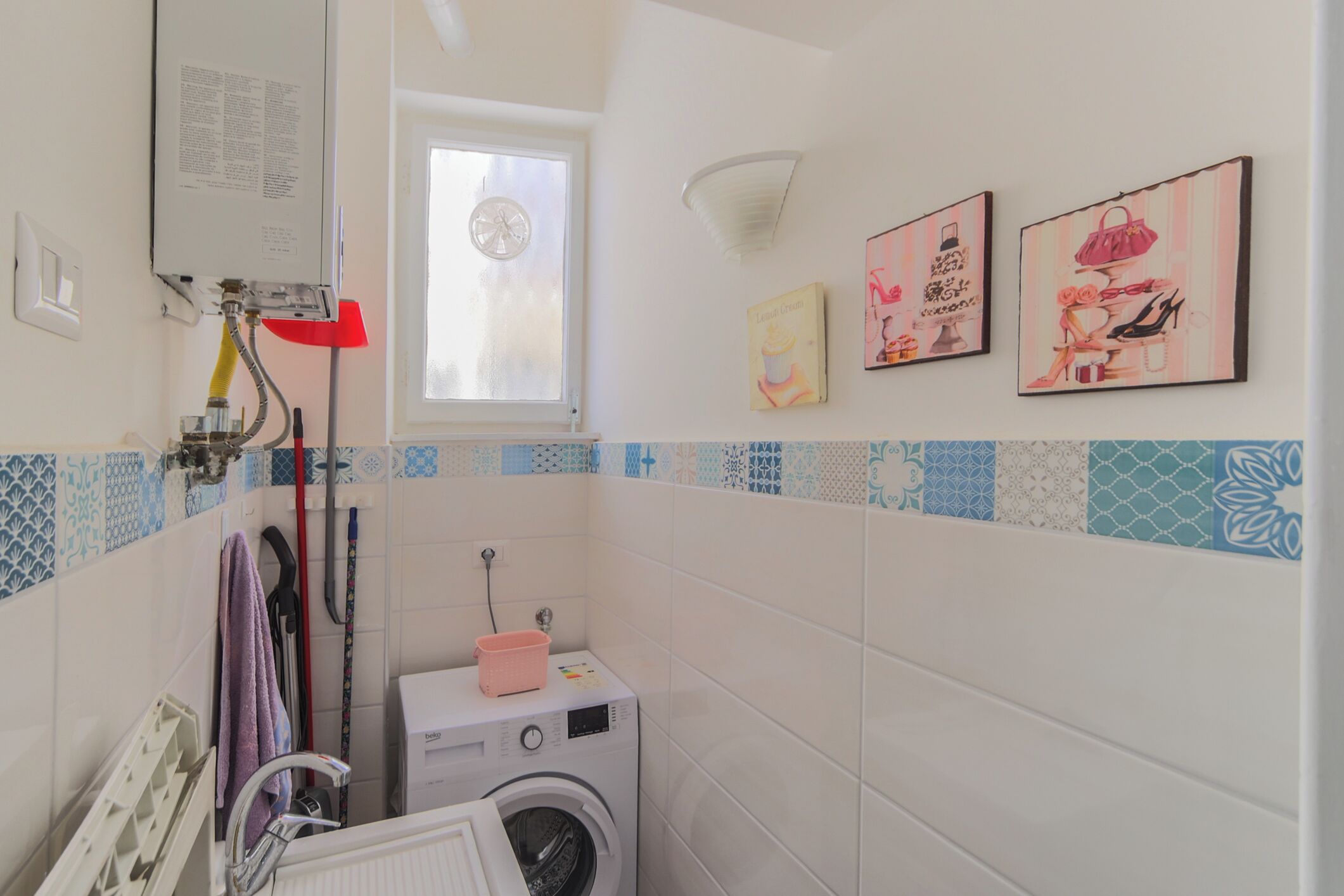 Un espace buanderie équipé d’un lave-linge, d’un étendoir et d’une fenêtre donnant sur un paysage agréable.