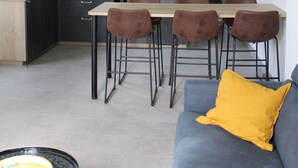 Eine moderne Küche mit Essbereich, einem Sofa mit gelbem Kissen und einer Kücheninsel.