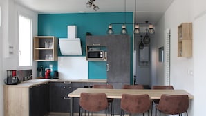 Eine moderne Küche mit einer Türkis-farbenen Akzentwand, einem Holzespeisetisch mit vier Stühlen und einem eingebauten Backofen.