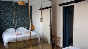 Ein modernes Hotelzimmer mit einem großen Bett, einem Spiegelkleiderschrank und einer Pendelleuchte.