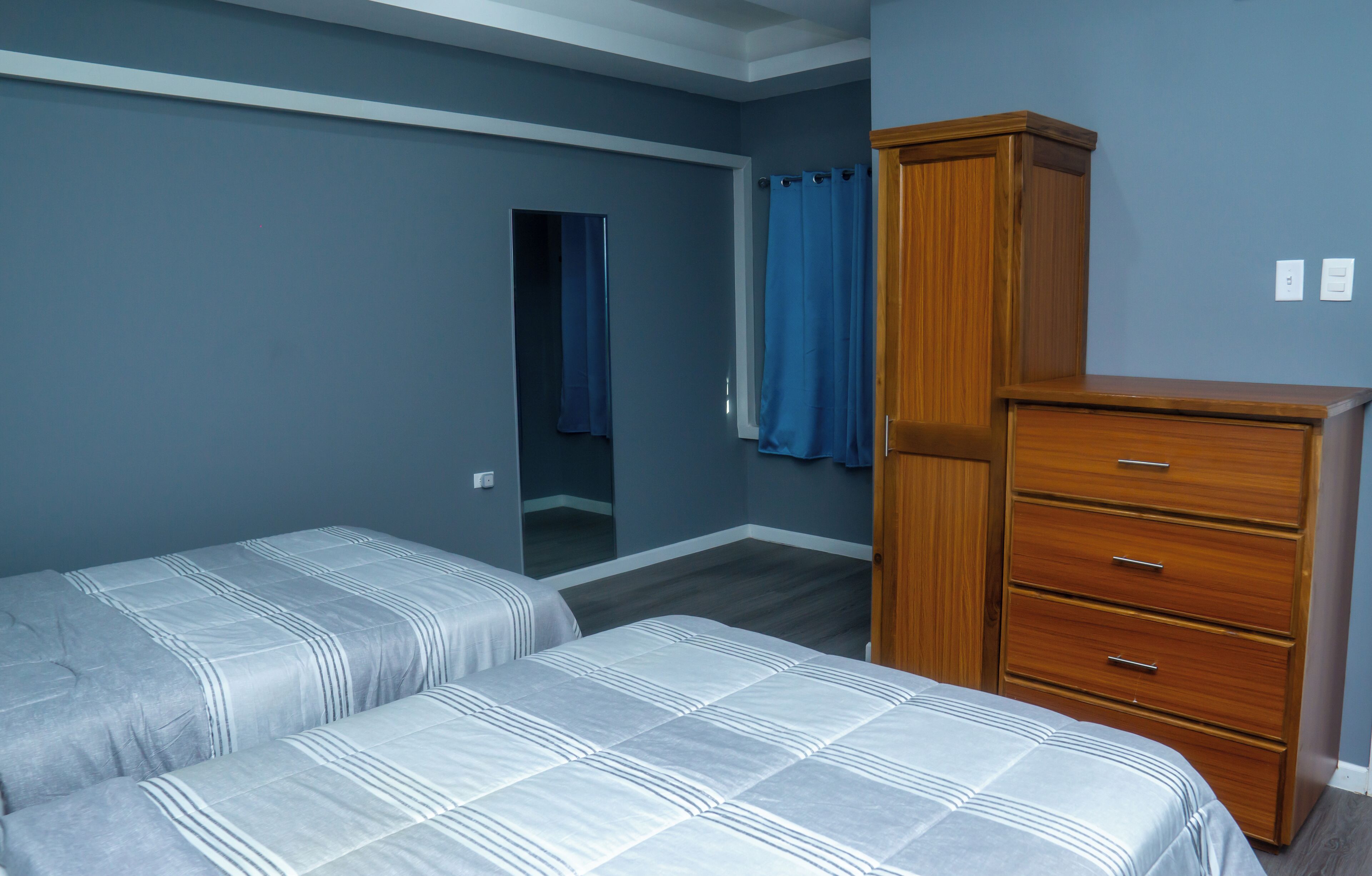 Un dormitorio con dos camas, un aparador de madera y un espejo.