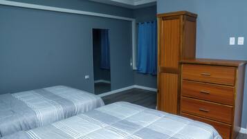 Un dormitorio con dos camas, un aparador de madera y un espejo.