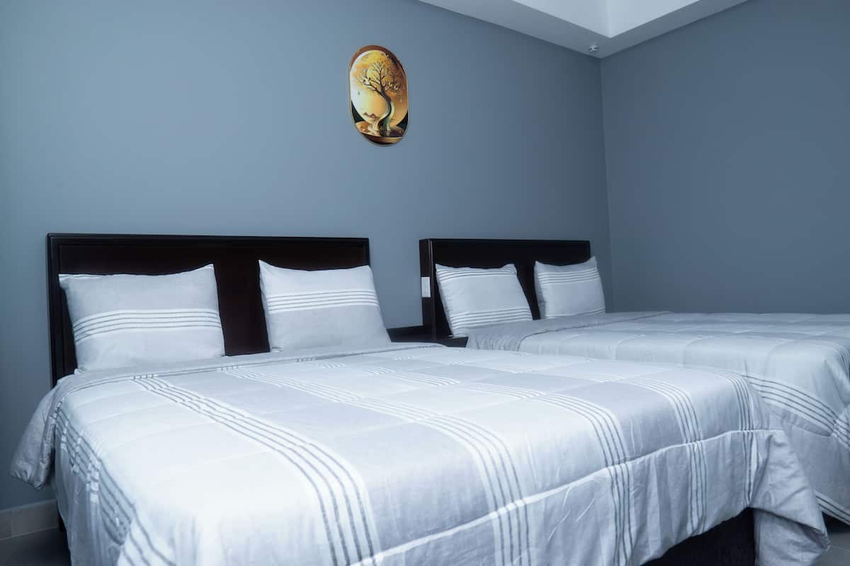 A hotel room with two beds, a dark headboard, and a wall-mounted artwork.
