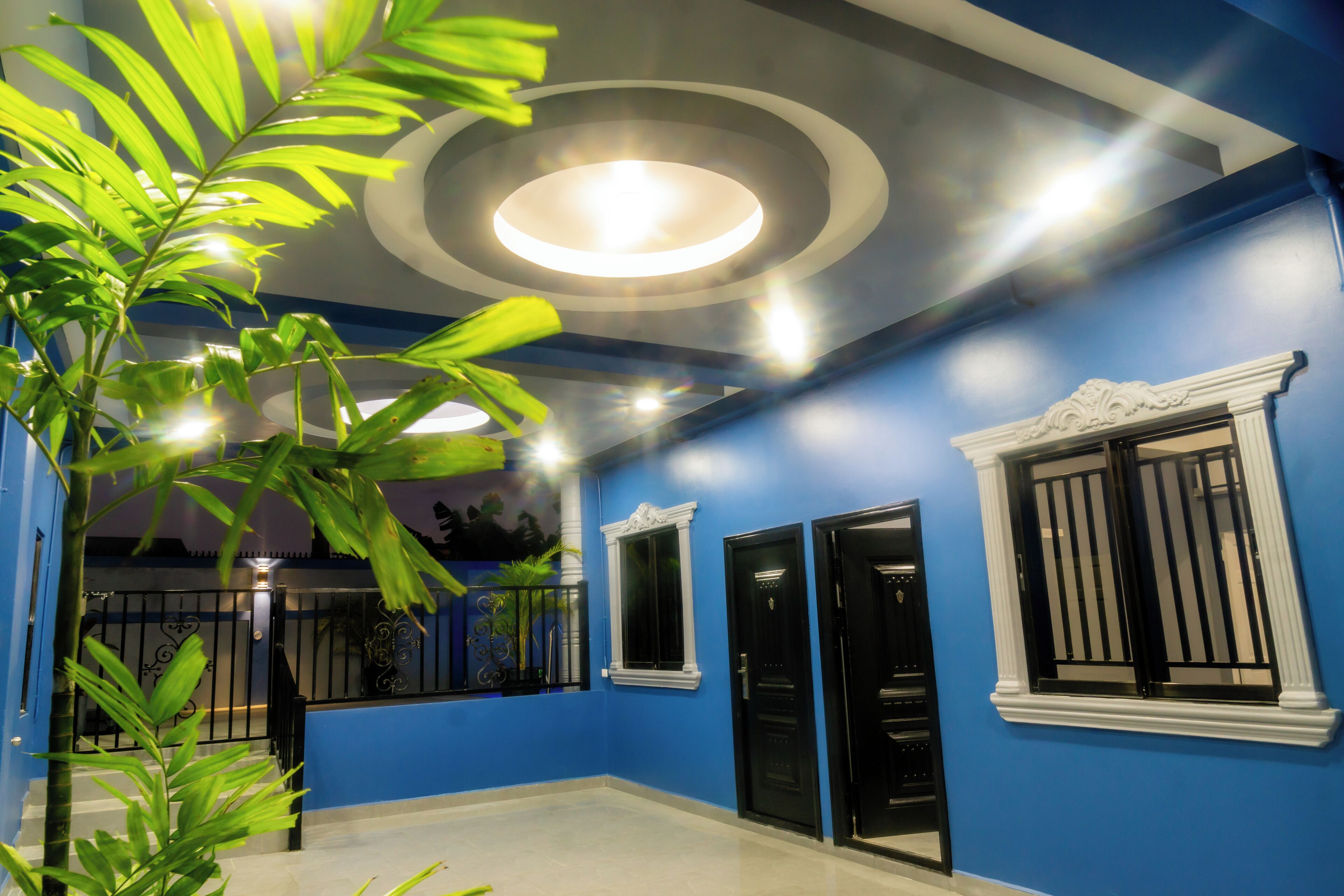 A room with blue walls, black doors, and a ceiling with circular lighting.