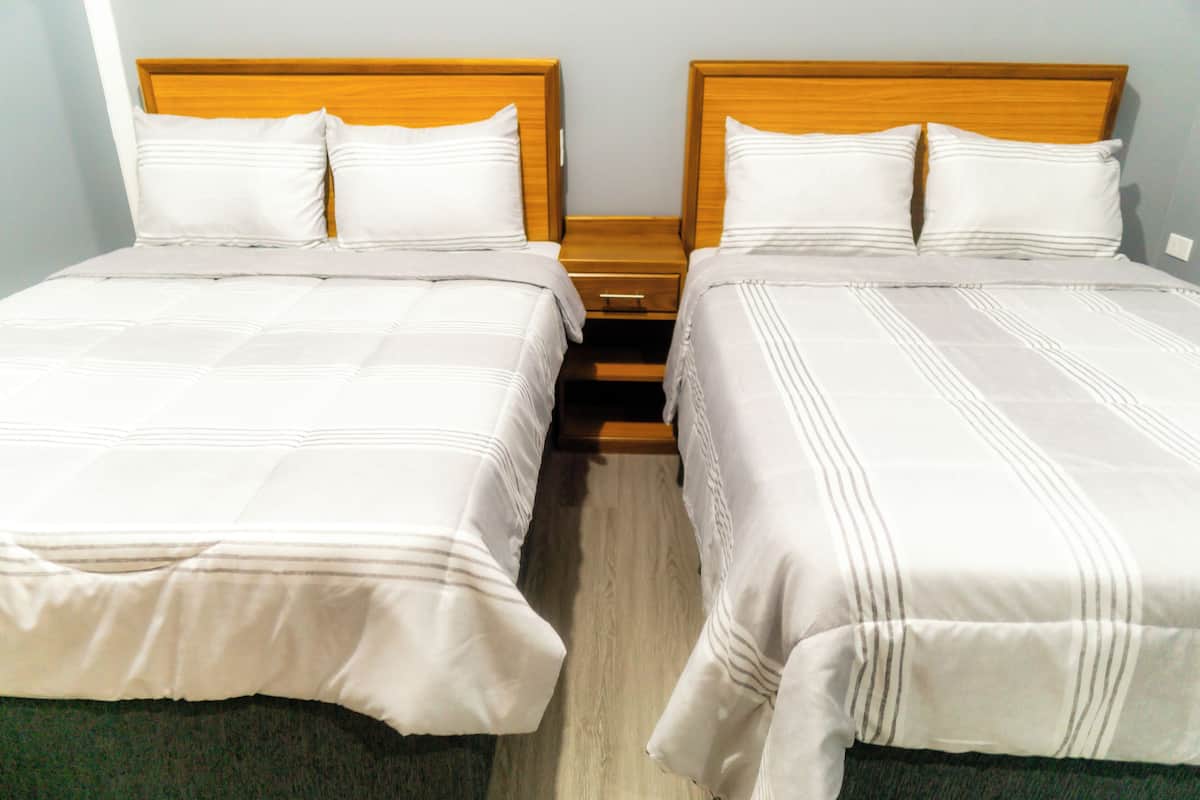 Two single beds with wooden headboards, white bedding, and a wooden nightstand between them.