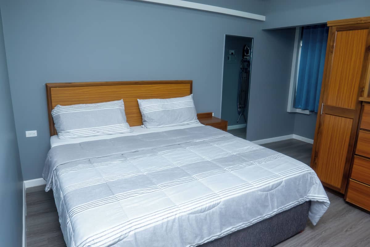 A bedroom with a large bed, wooden headboard, and a wardrobe.