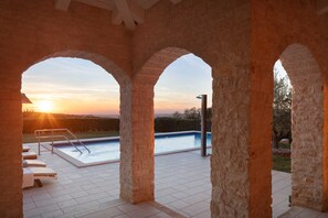 A pool area with a sunset view, stone arches, and a lounge with sunbeds. - Villa Sara Bajkini with vineyard view (Bajkini)
