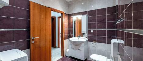 A modern bathroom with a bathtub, white sink, and toilet.