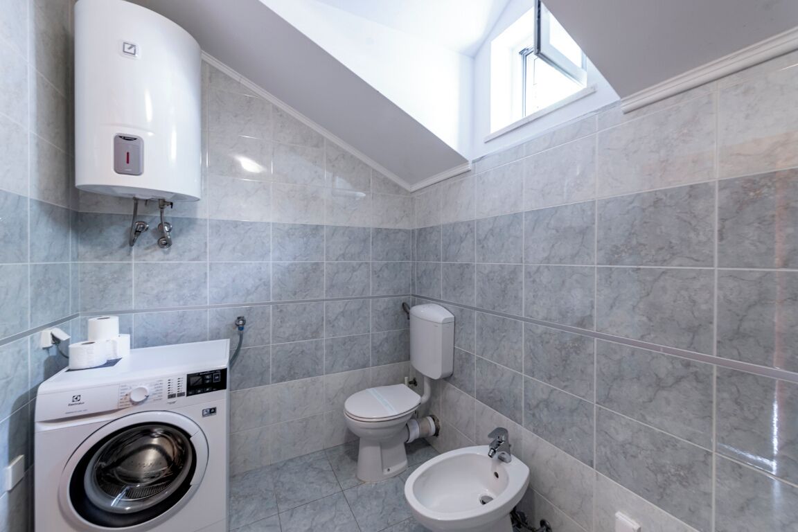Ein modernes Badezimmer mit Waschmaschine, Toilette, Bidet und Warmwasserbereiter.
