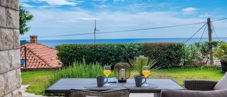 A patio with a table set for two, overlooking a coastal view.