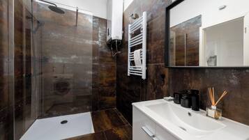 A modern bathroom with a glass-enclosed shower, a white sink, and a large mirror.