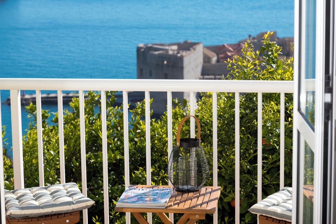 A balcony with a table, a lantern, and a cushion.