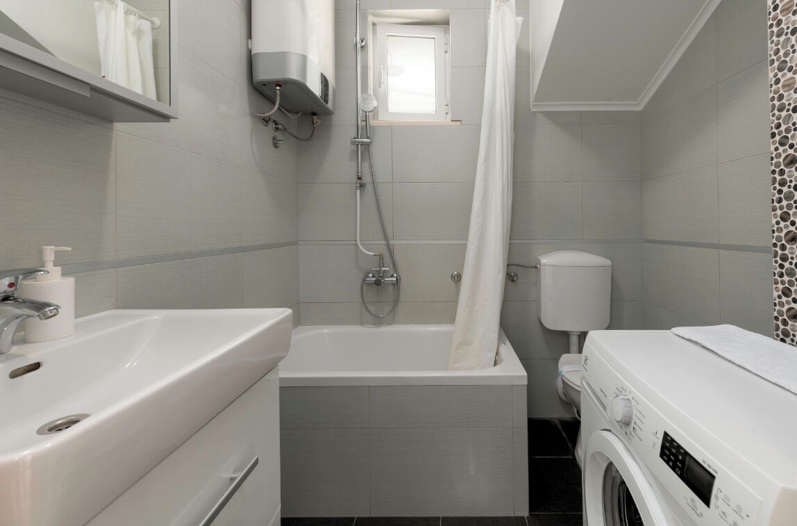 Un baño moderno con bañera, inodoro, lavadora y ducha.