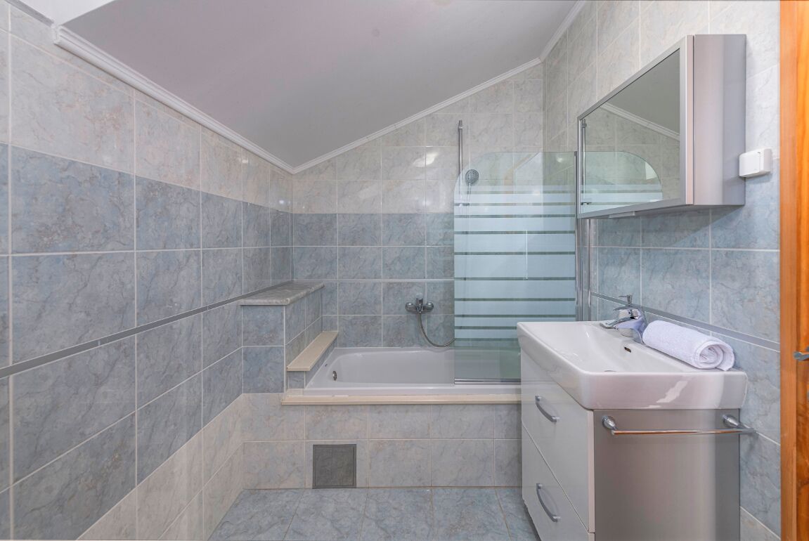 A modern bathroom with a bathtub, a glass shower enclosure, and a vanity with a mirror.