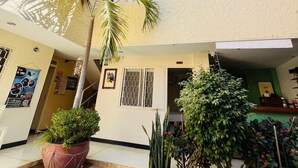A multi-level building with a central courtyard featuring potted plants and a palm tree. - Hotel Casa Dmer  (Taganga)