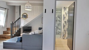 Ein modernes Wohnzimmer mit einer grauen Couch, einem Fernseher und einer Treppe zu einem anderen Raum.