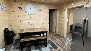 Un interior de madera con una mesa, un banco y un reloj en la pared.