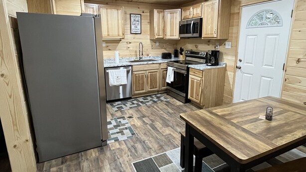 Una cocina compacta con armarios de madera, un refrigerador, un microondas y un lavamanos.
