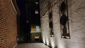 A wooden deck with a brick building on one side and a textured wall on the other.