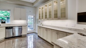 A modern kitchen with stainless steel appliances, white cabinetry, and a large island.