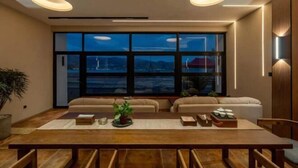 Una sala moderna con un ventanal grande, una mesa de comedor de madera y dos sofás.