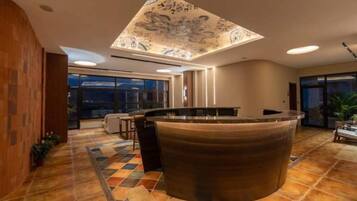Un moderno vestíbulo de hotel con un mostrador de recepción central, ventanas amplias y un techo con diseño.