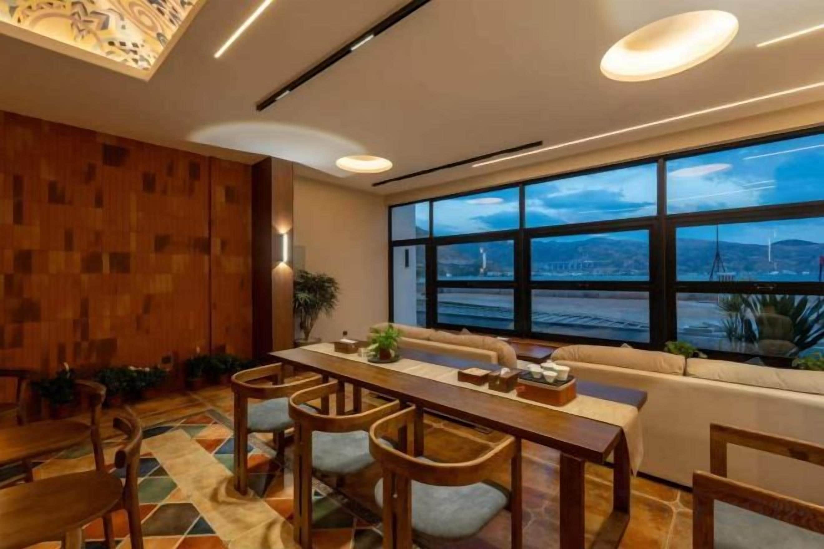 Un comedor moderno con una mesa larga, sillas de madera y vistas de la ciudad a través de amplios ventanales.