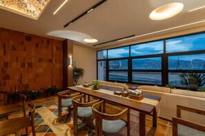 Un comedor moderno con una mesa larga, sillas de madera y vistas de la ciudad a través de amplios ventanales.