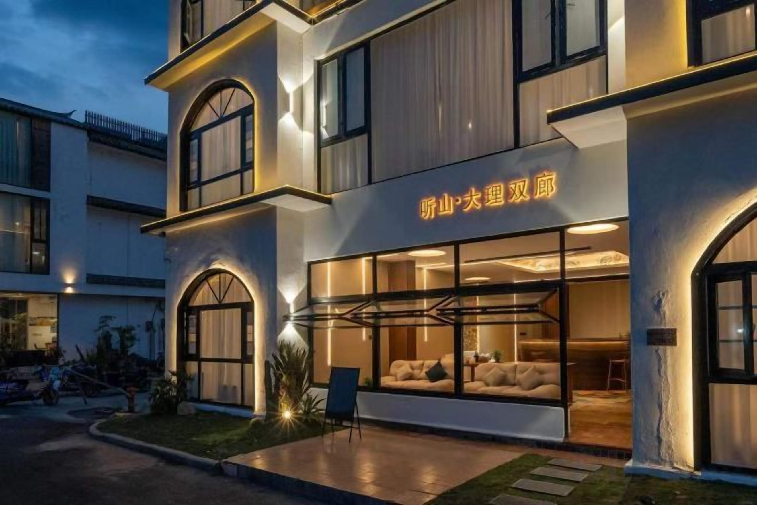 Un hotel con fachada moderna, grandes ventanales y un letrero con caracteres chinos.