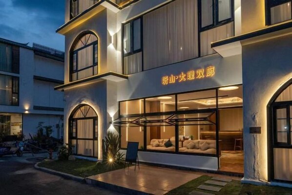 Un hotel con fachada moderna, grandes ventanales y un letrero con caracteres chinos.