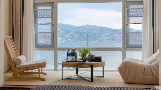 Una habitación con un amplio ventanal de arco, una mesa de madera, una silla acolchada y un sofá.